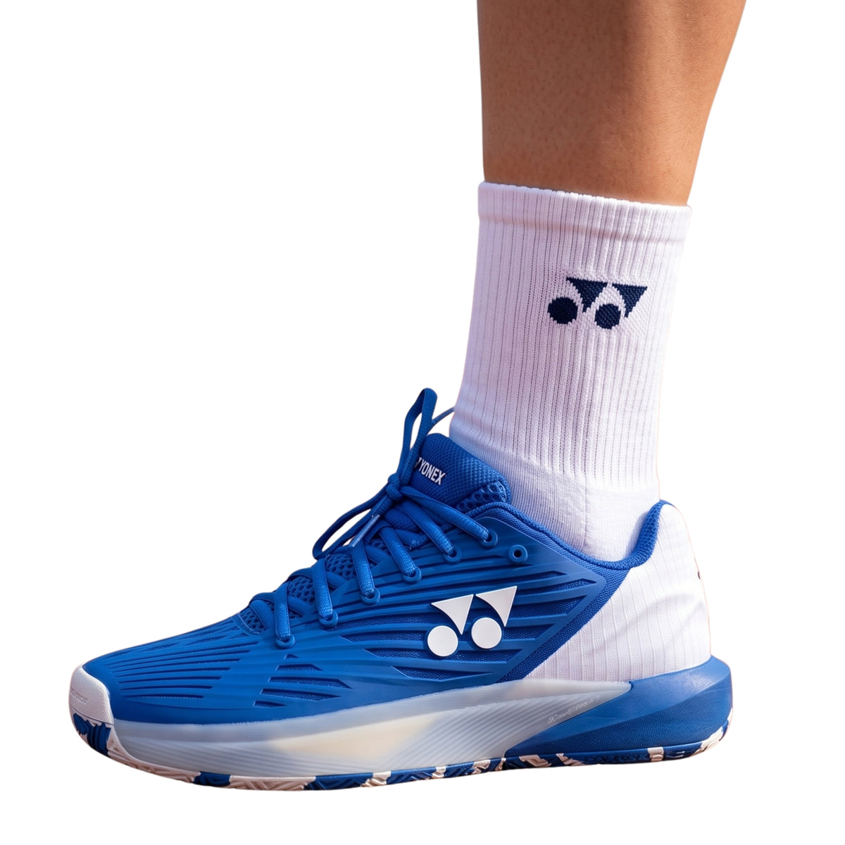 Blue athletic shoe with white sole worn with a white sock featuring a logo on a white background