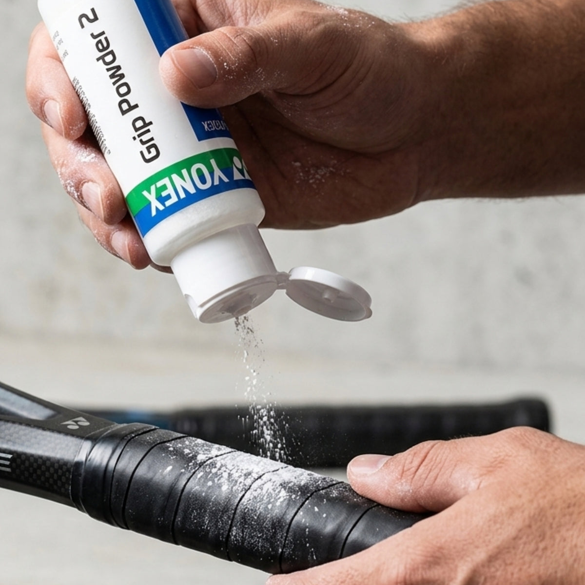 Person applying Yonex grip powder to a sports equipment handle