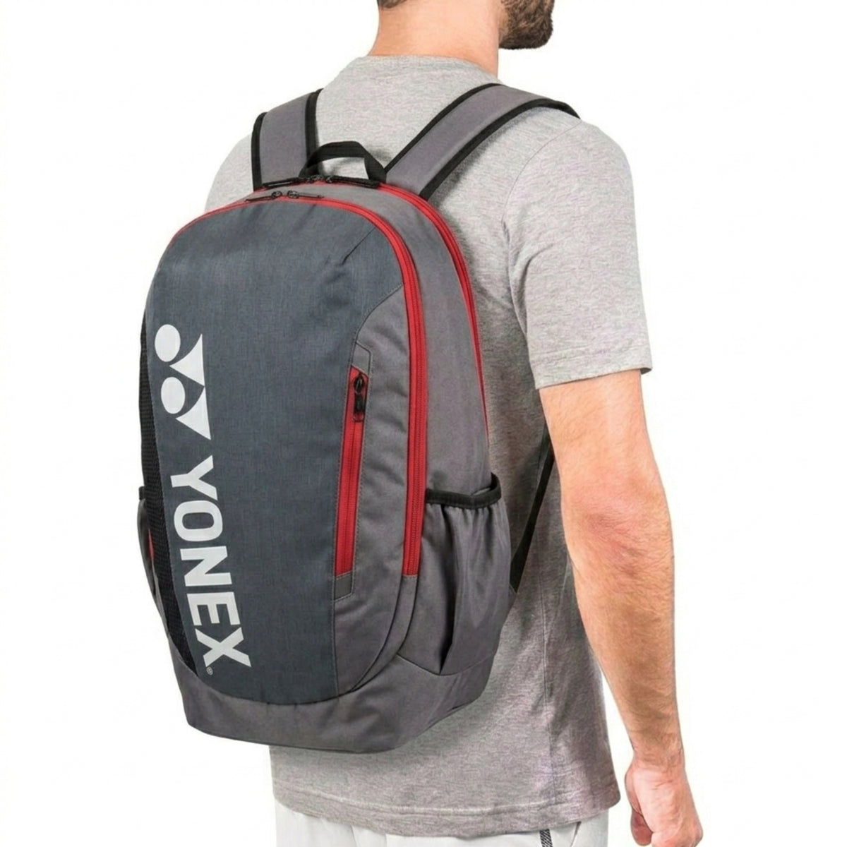 Person wearing a gray and red Yonex backpack on a white background