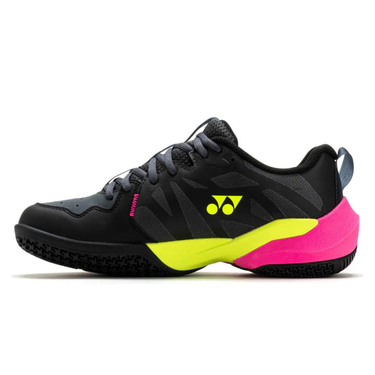 Black Yonex tennis shoe with pink and yellow sole on a white background