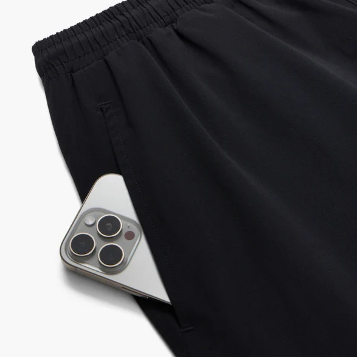 Black pants with a smartphone peeking out from the pocket on a white background