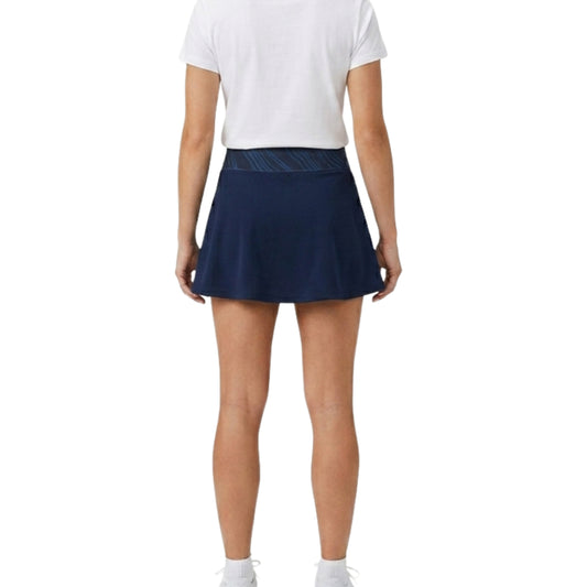 Person wearing a navy blue tennis skirt and white top on a white background
