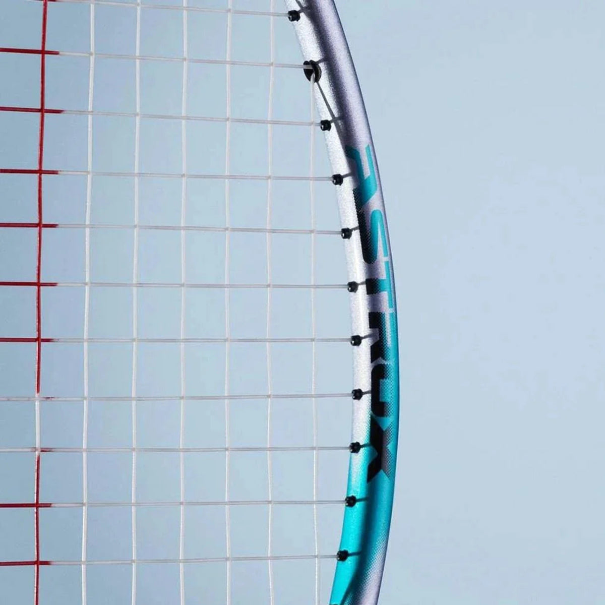 Close-up of a badminton racket against a blue sky with grid background