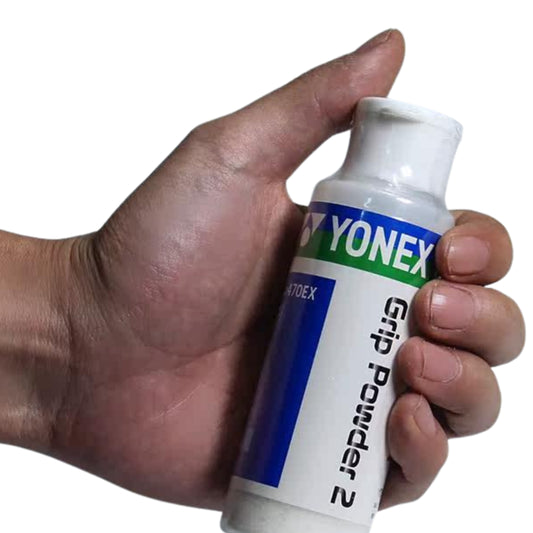 Hand holding a Yonex grip powder canister against a white background