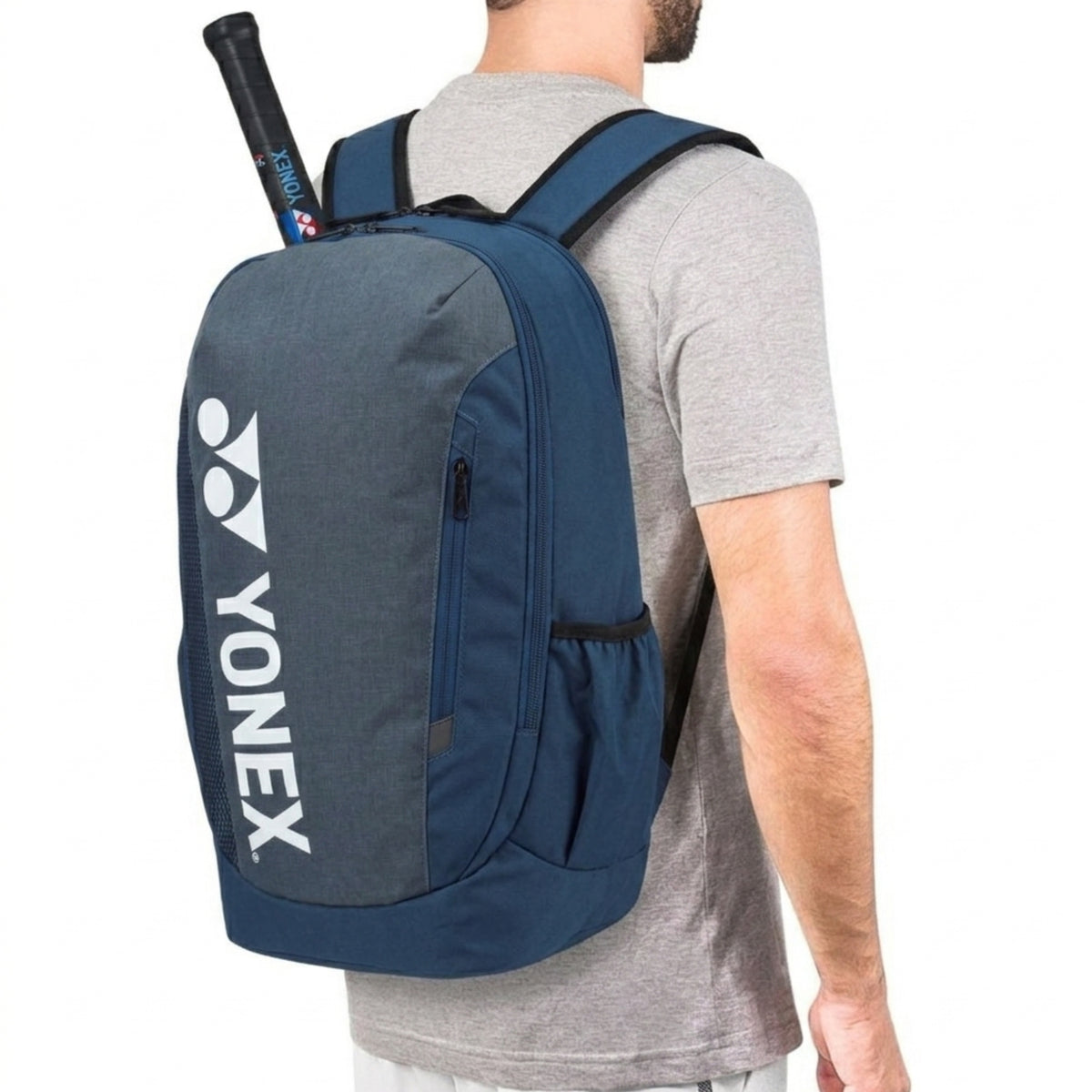 Person wearing a blue Yonex backpack with a tennis racket on a white background