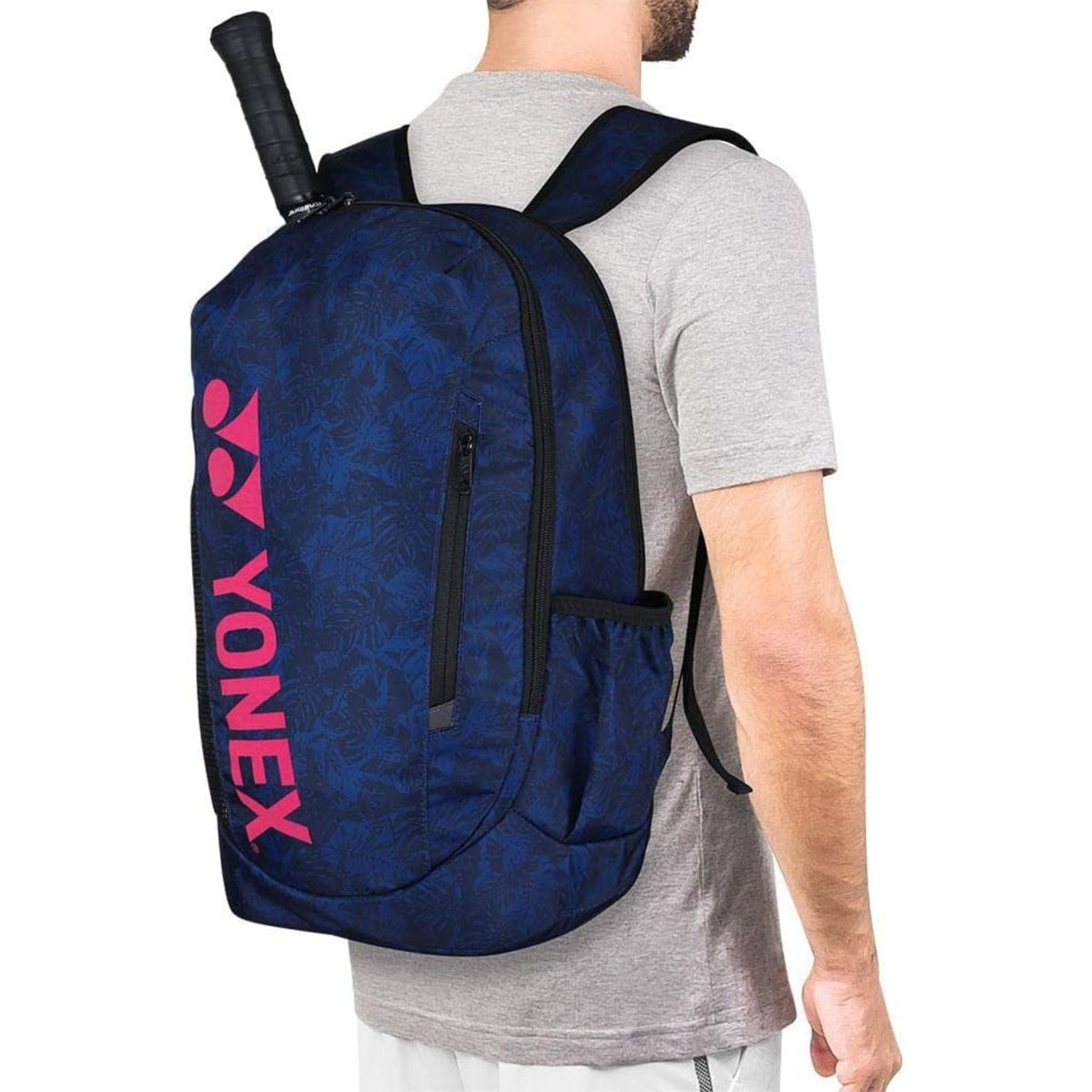 Person wearing a blue Yonex backpack with a racket on a white background