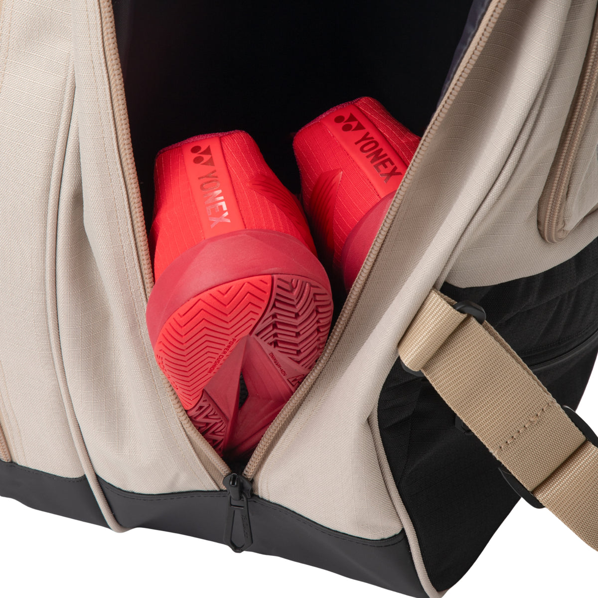 Red Yonex shoes inside a beige tennis bag