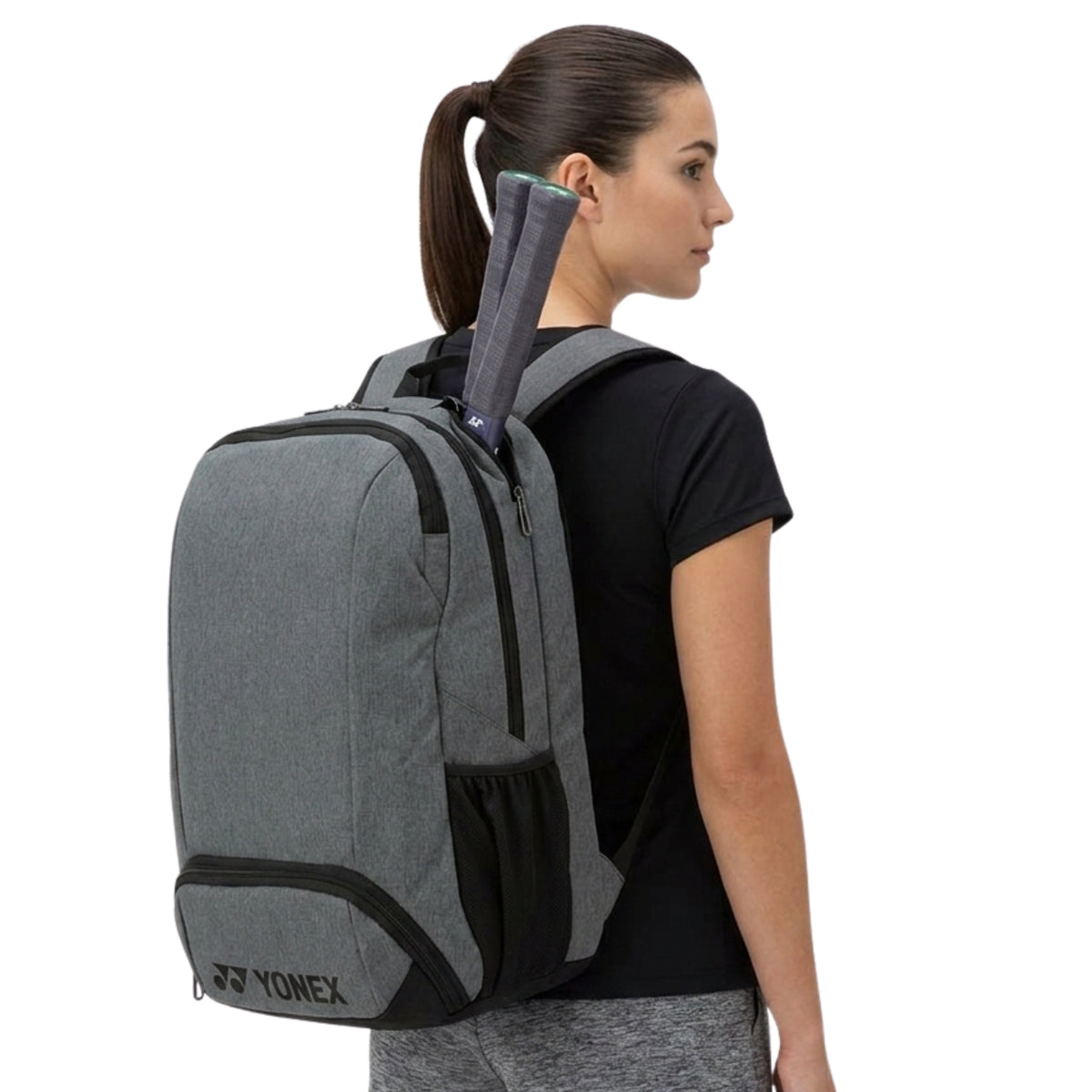 Woman wearing a gray Yonex backpack on a white background