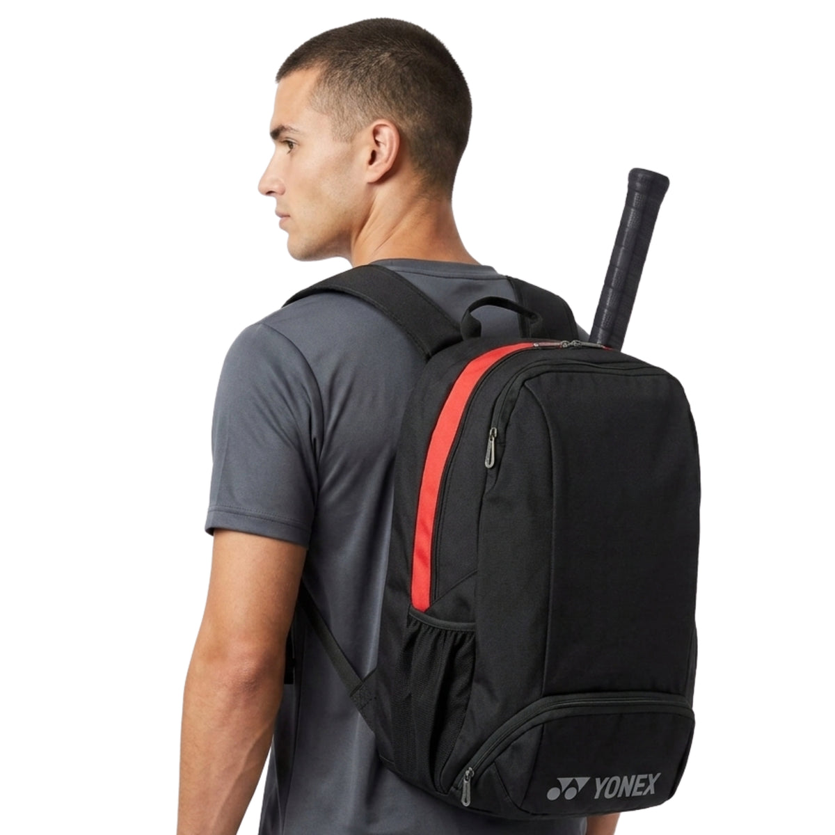 Man wearing a black backpack with a red stripe, holding a Yonex racket.