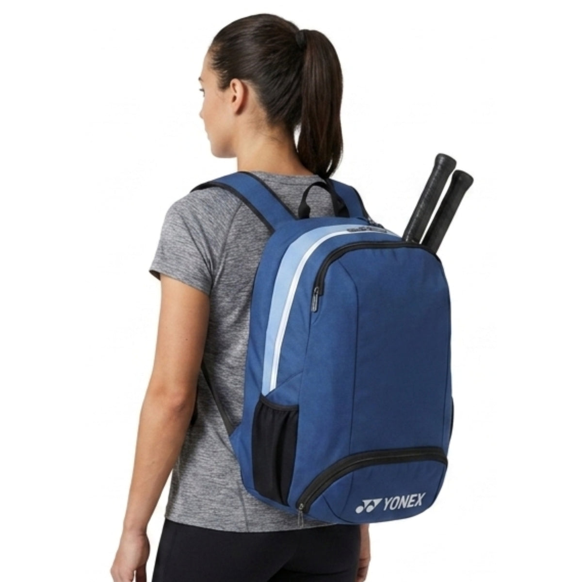 Person wearing a blue Yonex backpack with tennis rackets on a white background