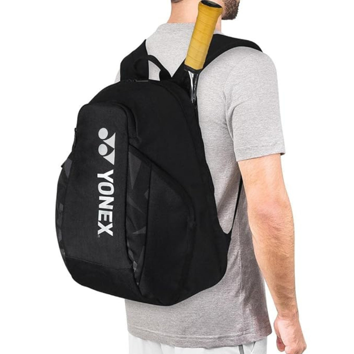 Person wearing a black Yonex backpack with a tennis racket on a white background