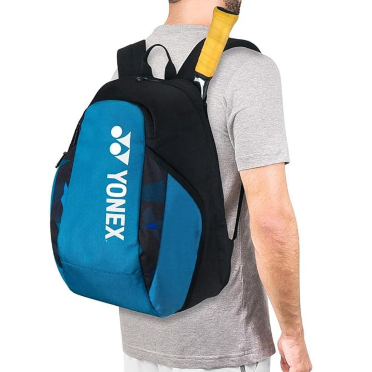 Person wearing a blue and black Yonex backpack with a tennis racket on a white background