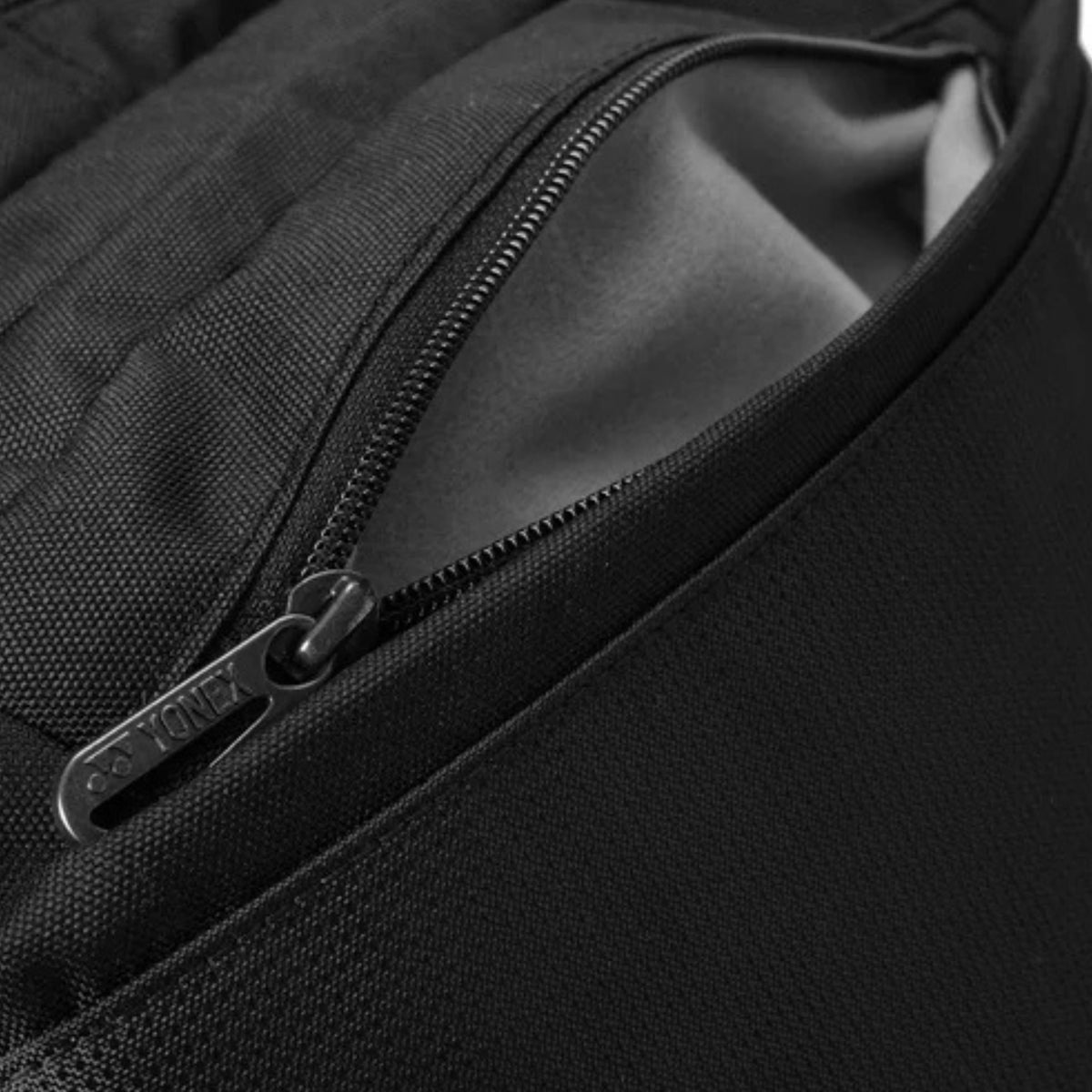 Close-up of a black backpack zipper with a brand logo.