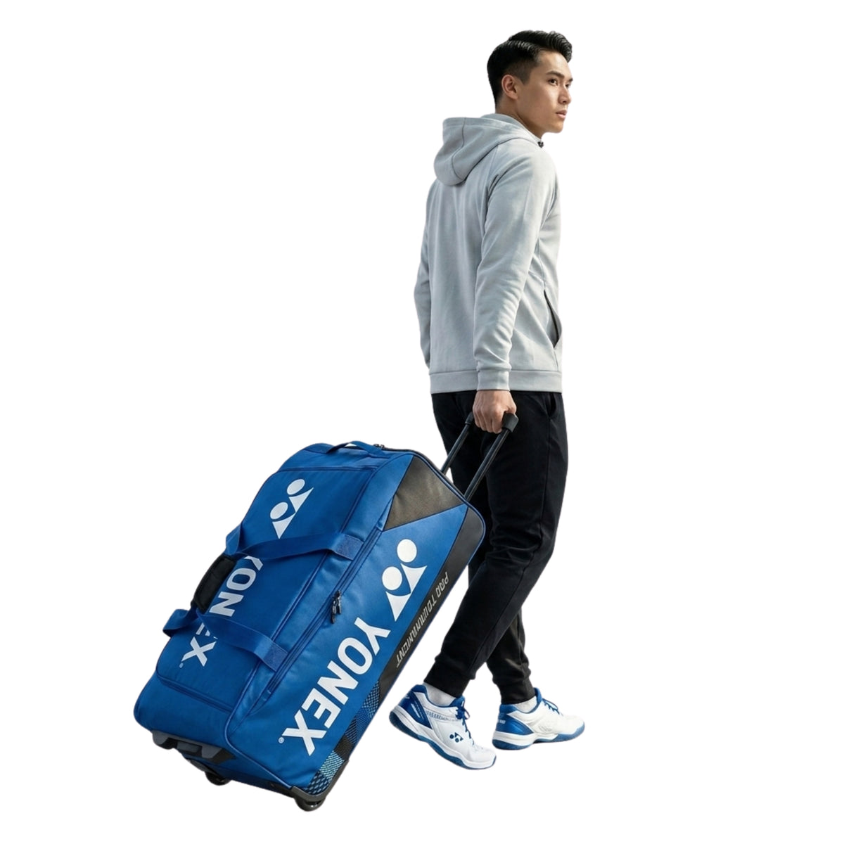 Person pulling a blue and black Yonex trolley bag with a visible brand logo on a white background