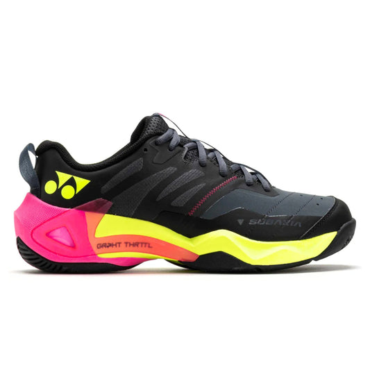 Black Yonex tennis shoe with pink and yellow sole on a white background