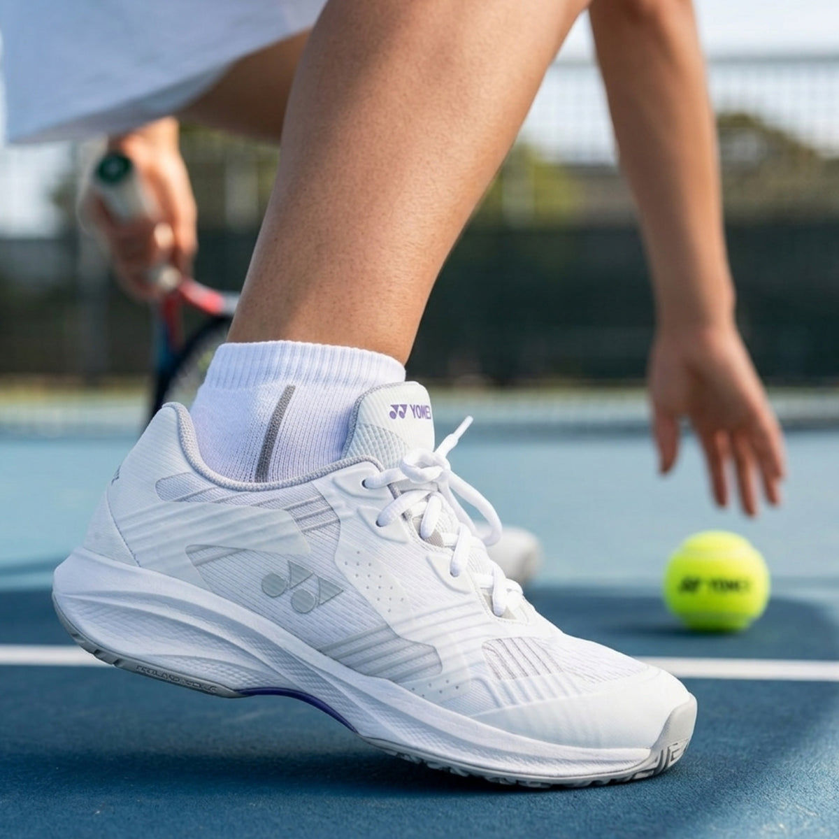 White Yonex tennis shoe with brand logo on a white background