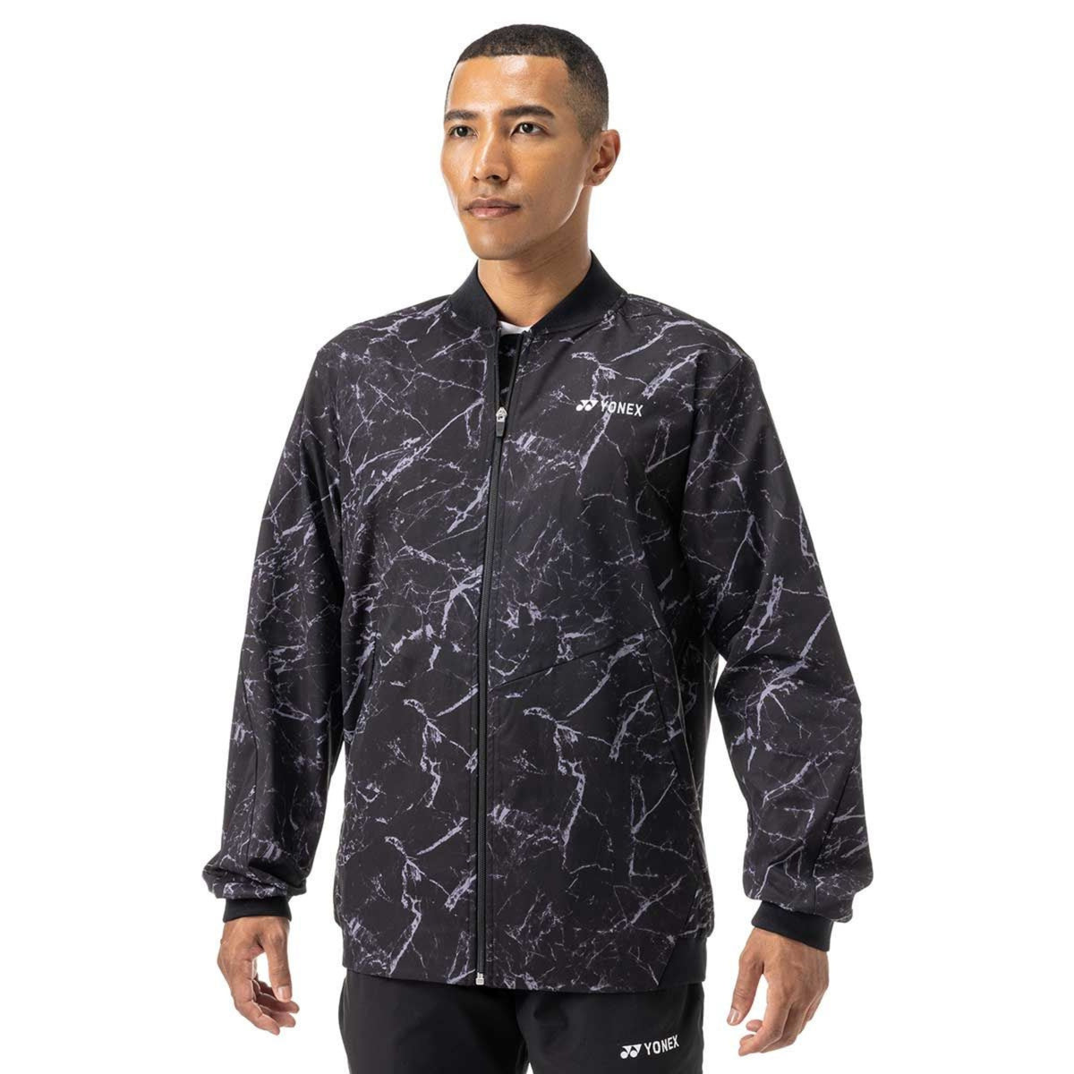 Man wearing a black patterned jacket with a brand logo on a white background