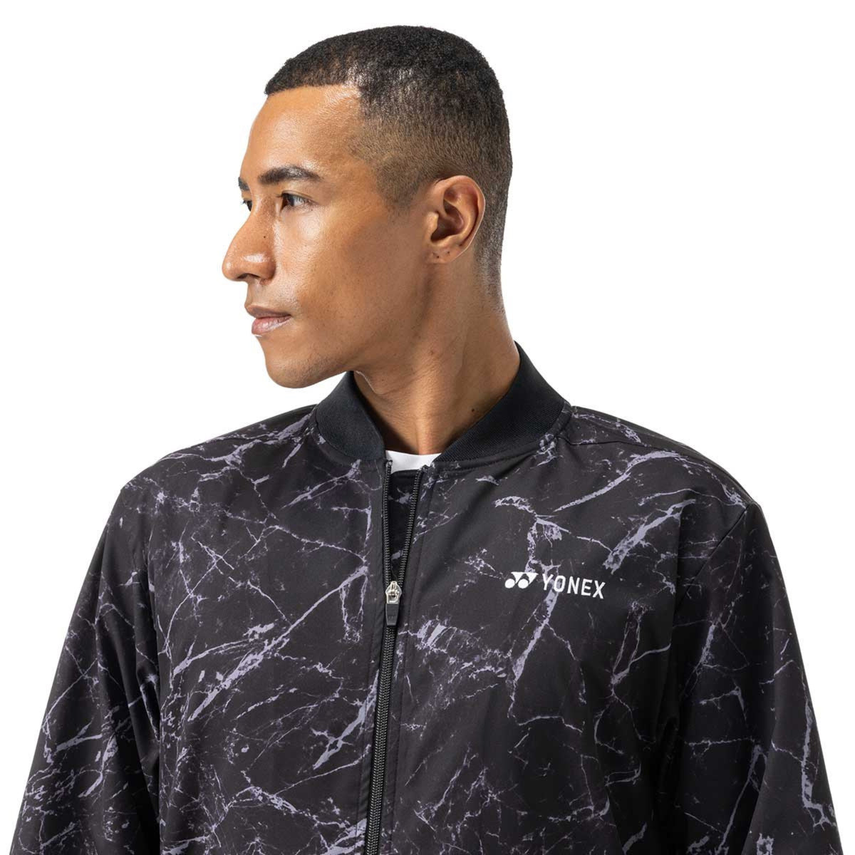 Man wearing a black and gray marbled pattern jacket with Yonex logo on a white background
