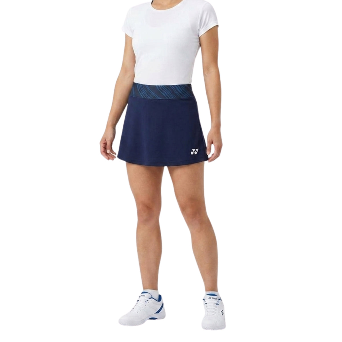 Person wearing a white shirt and navy tennis skirt with a brand logo on a white background